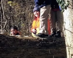 Maureen McCarthy smiles as 2nd grade students from Lafayette Preparatory Academy practice balancing on a fallen tree.