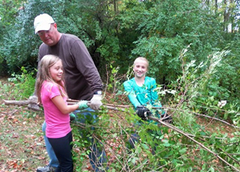 Girls working with community member to clear brush